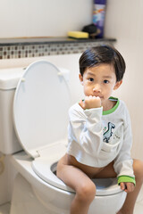 A boy is sitting on toilet with suffering.
