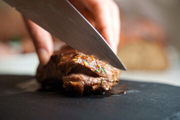 Woman cutting fried duck fillet with a knife.