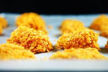Chicken nuggets on parchment paper before baking.