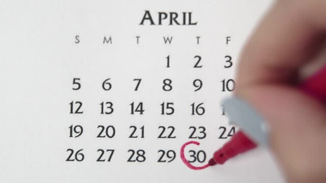 Female hand circle day in calendar date with a red marker. Business Basics Wall Calendar Planner and Organizer. APRIL 30th
