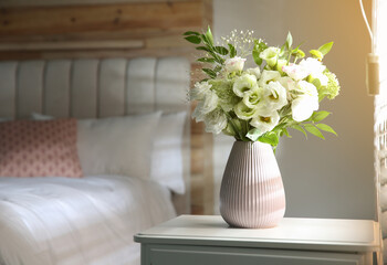 Bouquet of beautiful flowers on nightstand in bedroom, space for text. Interior design