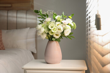 Bouquet of beautiful flowers on nightstand in bedroom. Interior design