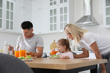 Happy family having breakfast together at table in modern kitchen