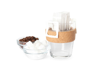 Glass cup with drip coffee bag, beans and sugar cubes isolated on white