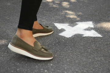 Woman standing near arrow on asphalt, closeup
