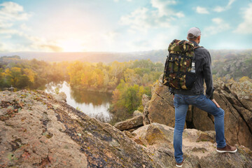 Fototapeta na wymiar Traveler with backpack enjoying beautiful view near mountain river. Autumn vacation