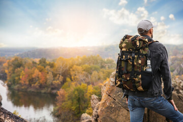 Fototapeta premium Traveler with backpack enjoying beautiful view near mountain river. Autumn vacation