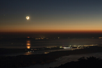 Moon setting above islands in Adriatic sea, view from the top of Velebit mountains.