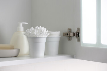 Fototapeta na wymiar Cotton buds and different toiletries on shelf indoors