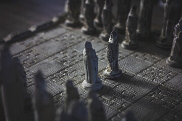 A portrait of a stone chess board. The game of strategy is just begon with two pawns of each army...