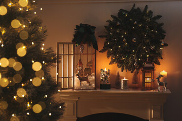 Beautiful wooden lanterns, festive wreath and other decorations in room with Christmas tree