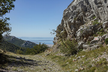Path by the rock in Velebit national park with sea in the background.