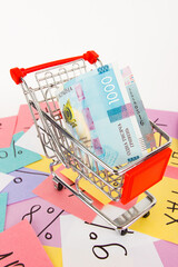 Shopping cart on the background of colored stickers with financial signs and symbols