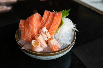 Raw sashimi salmon sliced and smoked salmon on ice in bowl