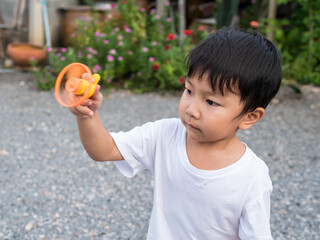 Asian child boy playing a flying spinner toy outdoor with cute face. Concept of freedom, family...
