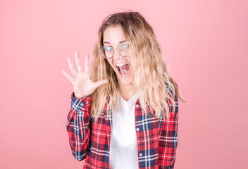 A young girl in a red shirt with crazy eyes makes a grimace on her face, smiling, waving.