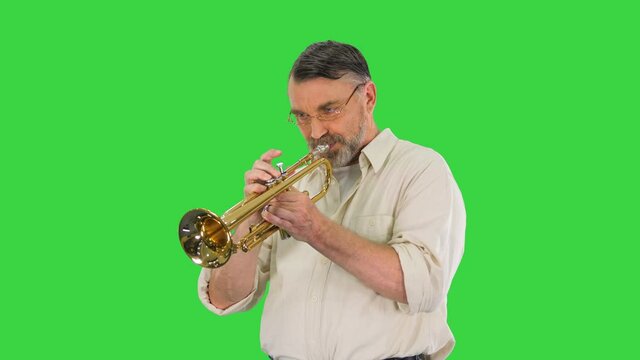 Senior musician playing a trumpet on a Green Screen, Chroma Key.