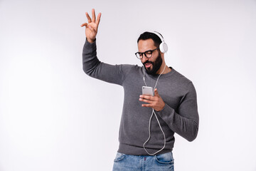 Fototapeta premium Handsome Arabian young boy listening to the music and dancing in headphones isolated over white background