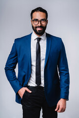 Vertical shot of a handsome middle east man in formal suit isolated over grey background