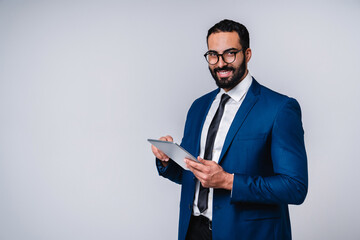 Confident young Middle Eastern businessman using tablet isolated over gray background