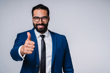 Cheerful young middle eastern businessman showing thumb up isolated over grey background