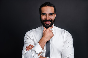 Pensive happy young arab businessman in formal shirl isolated over black background