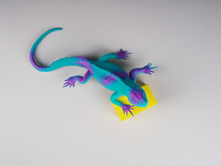 Fototapeta premium toy iguana lizard on a gray and yellow background, concept photo, space for text