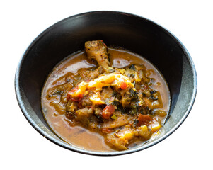 Chakhokhbili (traditional georgian dish from stewed chicken meat, tomato, eggplant and fresh herbs) in black bowl cutout on white background