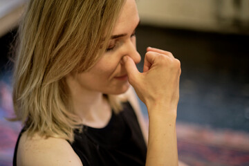 Breathing with a change of nostril. middle aged woman doing breathing exercises yoga, meditation,...
