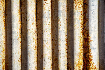 Rusted corrugated sheet metal siding background showing its age and weathering.