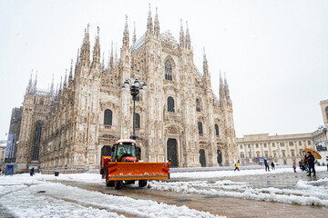 Tractor used as a snowplow under heavy snowfall removing the snow in the Milan Cathedral square,...