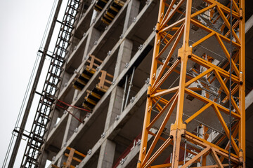 Obraz premium Yellow construction crane attached to the wall of an office building under construction