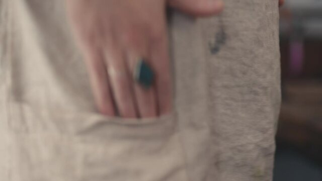 Closeup, woman putting hands in pockets of brown burlap or jute frock