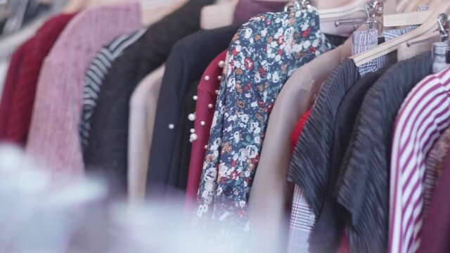 Panning movement of second hand clothing hanging in a thrift shop. Racking Focus with camera panning movement. Shot in 4K.