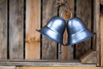 Two large, silver, decorative bells hanging inside wooden boxes