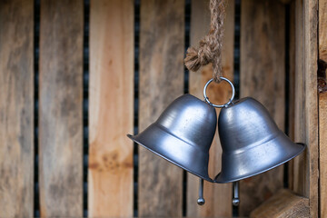 Two large, silver, decorative bells hanging inside wooden boxes