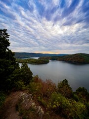 Fototapeta na wymiar Hawn’s Overlook of Raystown Lake in the mountains of Pennsylvania in the fall right before sunset with a dramatic blue swirly sky with orange tones in it and water as smooth as glass.