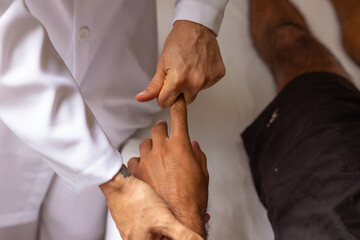 Detalhe de massoterapeuta fazendo massagem em mão de paciente.