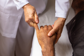 Detalhe de massoterapeuta fazendo massagem em mão de paciente.