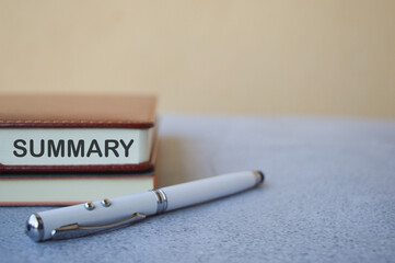 Selective focus with blurred effect of pen and notebooks written with text SUMMARY. Business and...