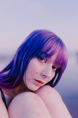 beautiful caucasian girl with dyed hair closeup photo lying relaxed on a salt lake with purple colors and natural light 