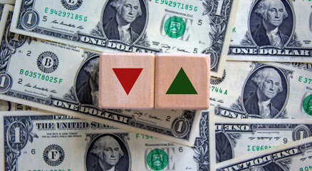 Conceptual image of choice and direction. Wooden blocks with arrows pointing in opposite directions. Beautiful background from dollar bills, copy space. Business and choice and direction concept.