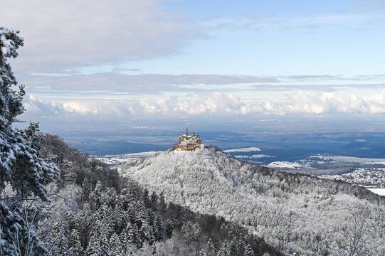 Snow covered, forested mountain ranges in Southern Germany. The Hohenzollern Castle is on a hill in the background.
