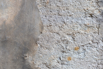 Der Putz zerfällt aus der Wand einer grauen Wand. Textur Muster einer zerbröckelnden Hausfassade. zerstörte Hausfassade