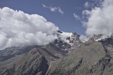 The peak of a snow capped mountain topped by clouds in the Italian Alps (Trentino, Italy, Europe)