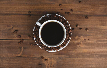 A cup of coffee surrounded by coffee beans.
