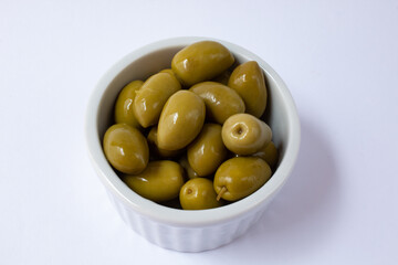 Pickled green olives in white bowl on white background