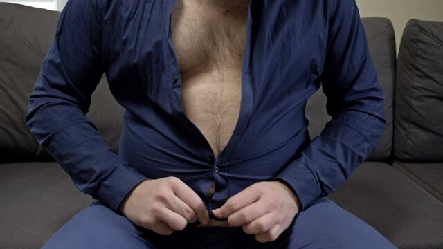 Overweight man tries unsuccessfully to button his shirt. Overweight problem.