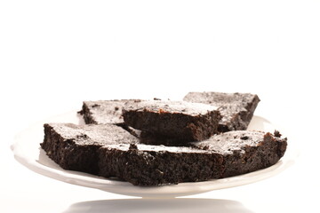 Several chocolate brownies with cherries on a white plate, close-up, on a white background.