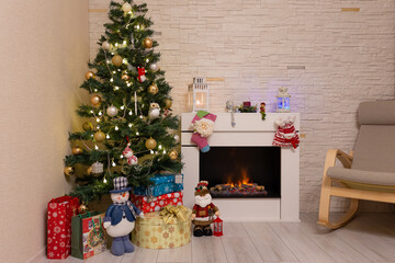Decorated Christmas tree, gifts in boxes, a Santa Claus statuette, a burning fireplace. New Year, Christmas. Selective focus.